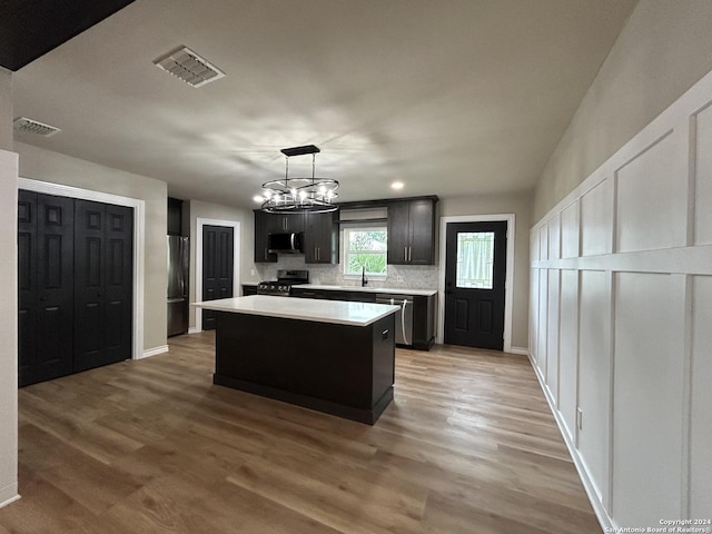 kitchen with dark wood-type flooring, pendant lighting, a center island, stainless steel appliances, and an inviting chandelier