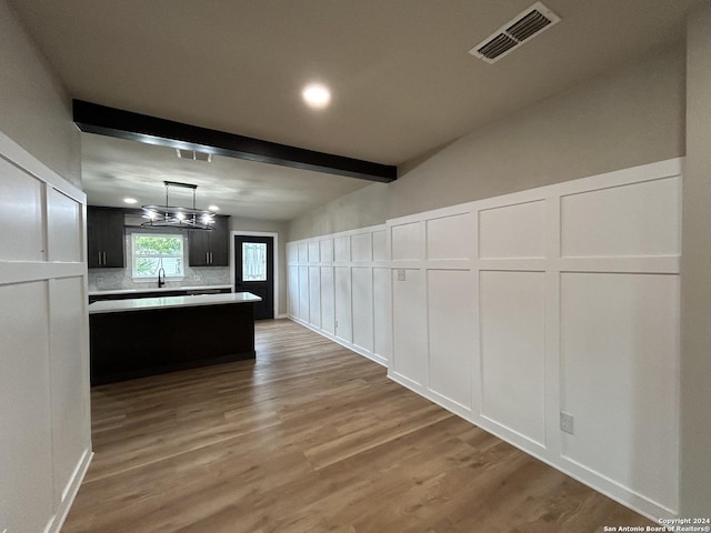 interior space with sink, an inviting chandelier, hardwood / wood-style floors, and beam ceiling