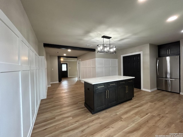 kitchen with light hardwood / wood-style flooring, a chandelier, hanging light fixtures, a kitchen island, and stainless steel refrigerator