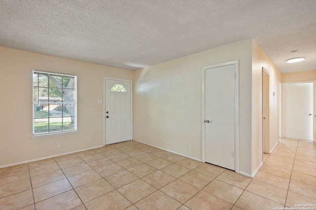 entrance foyer with light tile patterned flooring and a textured ceiling