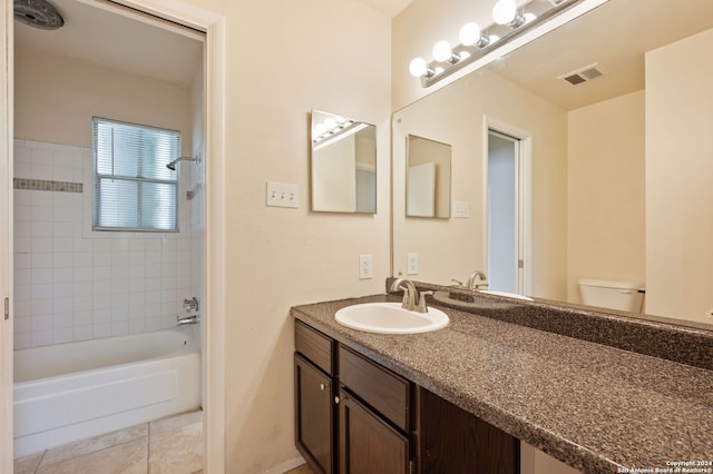 full bathroom featuring tile patterned flooring, tiled shower / bath combo, vanity, and toilet