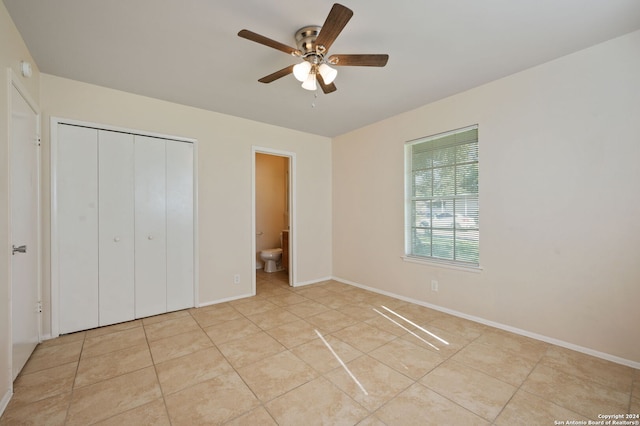 unfurnished bedroom featuring connected bathroom, light tile patterned flooring, a closet, and ceiling fan