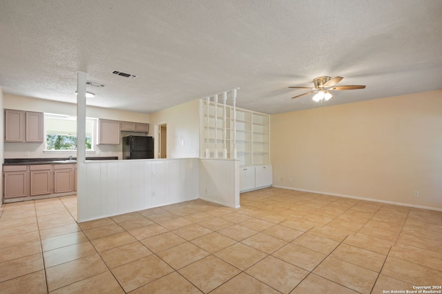 kitchen with black refrigerator, a textured ceiling, ceiling fan, and light tile patterned floors