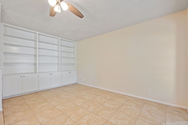 tiled spare room with a textured ceiling, ceiling fan, and built in features