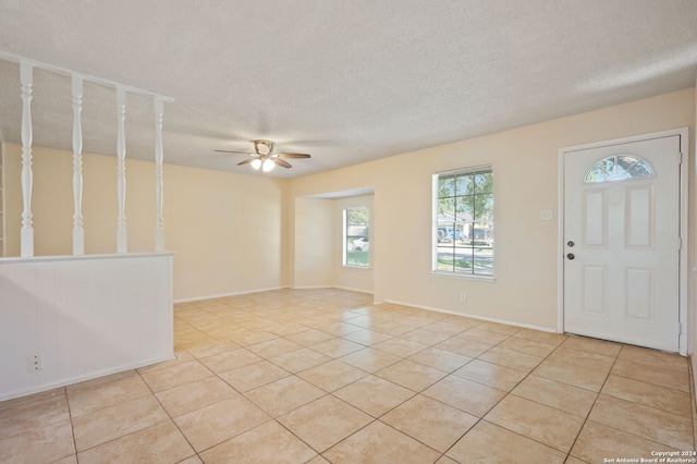 tiled foyer entrance with a textured ceiling and ceiling fan