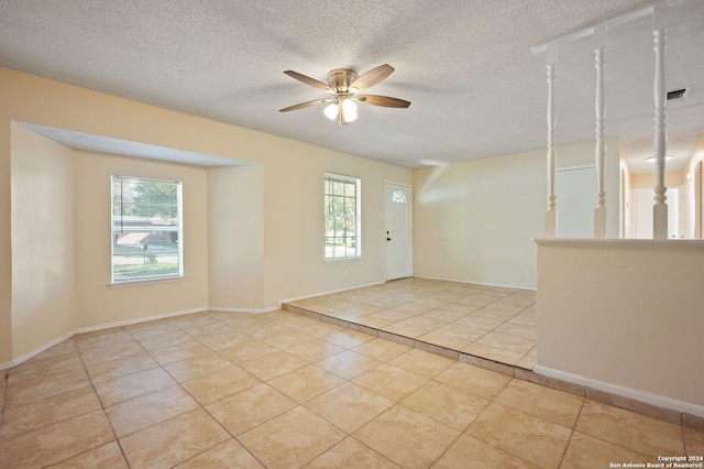 tiled spare room with a textured ceiling and ceiling fan