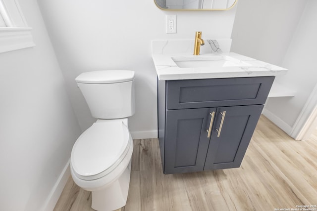 bathroom with wood-type flooring, vanity, and toilet