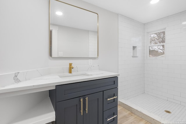 bathroom featuring a tile shower, vanity, and hardwood / wood-style floors