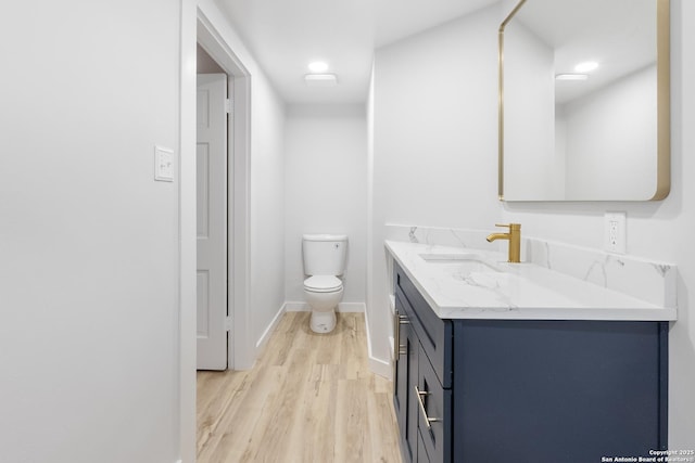 bathroom with wood-type flooring, vanity, and toilet