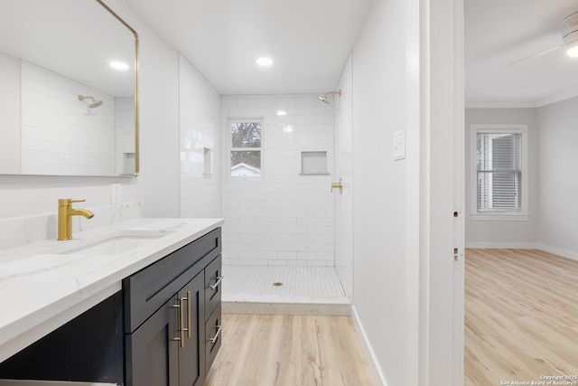 bathroom featuring ceiling fan, tiled shower, wood-type flooring, and vanity