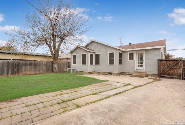 rear view of property with central air condition unit and a yard