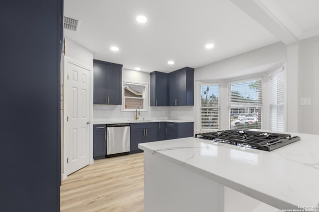 kitchen featuring appliances with stainless steel finishes, kitchen peninsula, light stone countertops, sink, and light hardwood / wood-style flooring