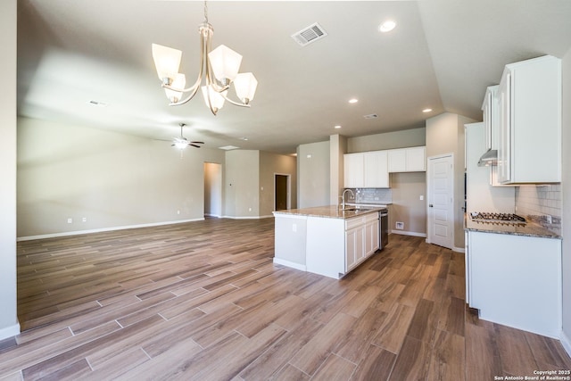 kitchen featuring light hardwood / wood-style flooring, a center island with sink, tasteful backsplash, ceiling fan with notable chandelier, and white cabinets