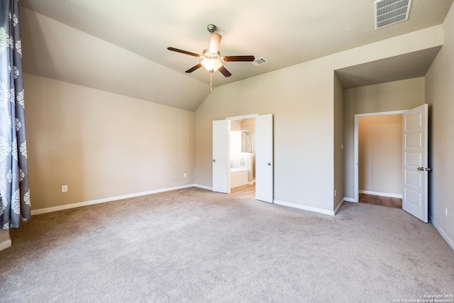 unfurnished bedroom featuring ceiling fan, connected bathroom, lofted ceiling, and light carpet