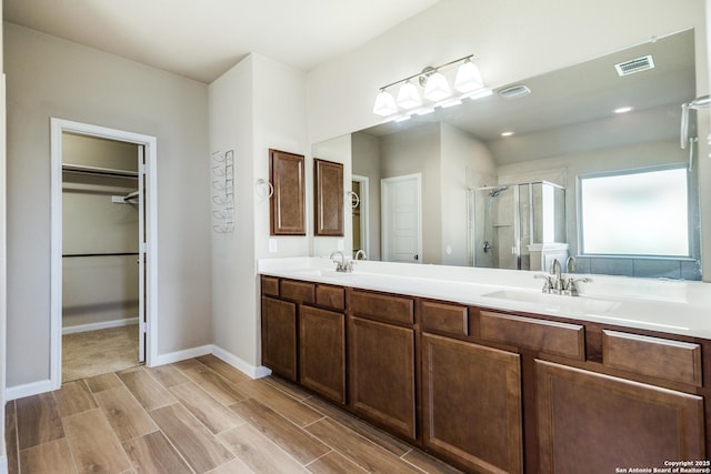 bathroom featuring a shower with door and vanity