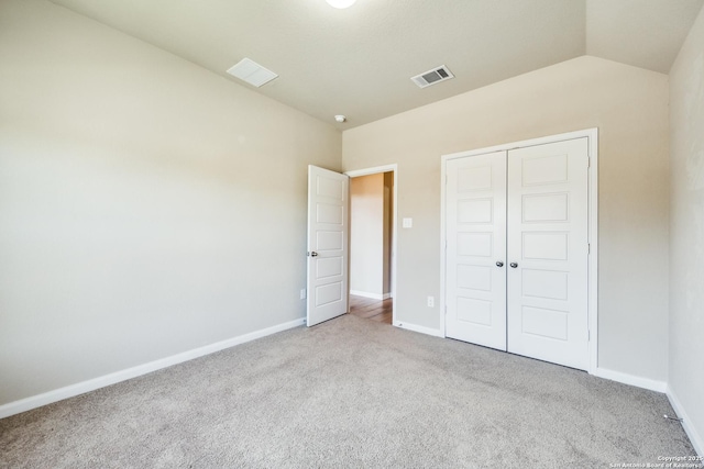 unfurnished bedroom with a closet, vaulted ceiling, and light colored carpet