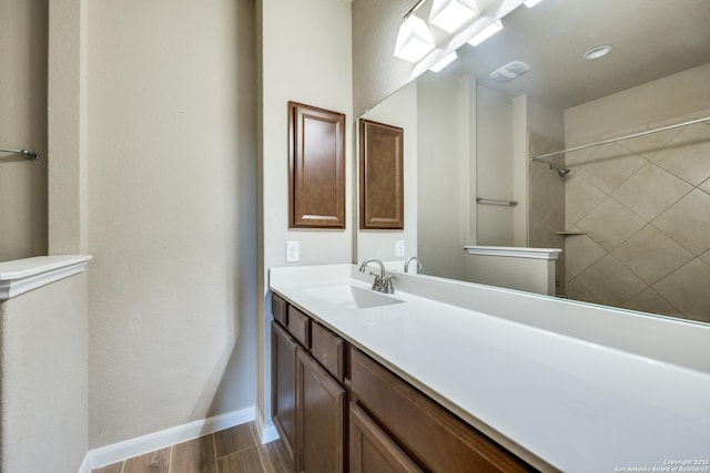 bathroom featuring tiled shower and vanity