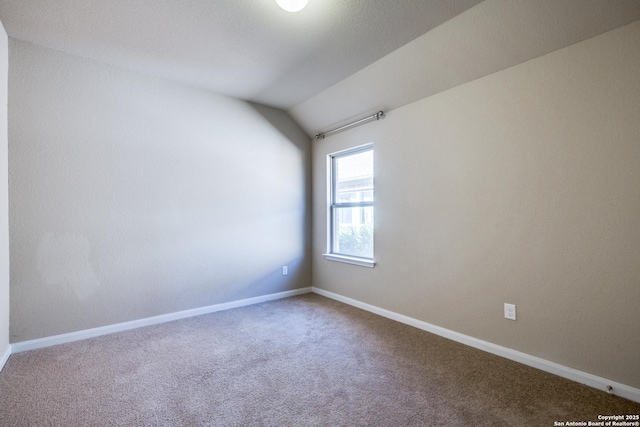 carpeted spare room with lofted ceiling