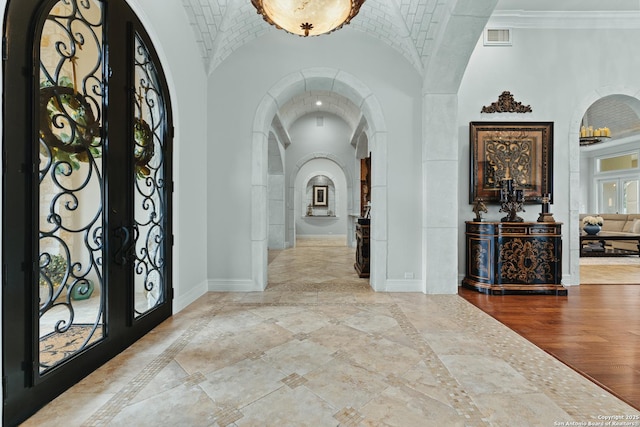 foyer with lofted ceiling, hardwood / wood-style flooring, brick ceiling, and french doors