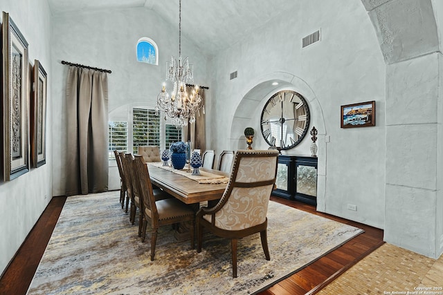 dining area with dark hardwood / wood-style flooring, a towering ceiling, and a chandelier