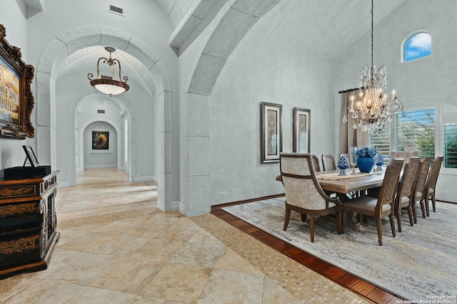 dining area with an inviting chandelier and a towering ceiling