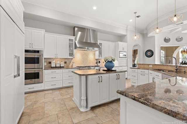 kitchen featuring white cabinetry, decorative backsplash, range hood, and a kitchen island