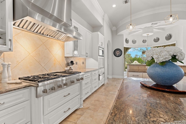 kitchen featuring hanging light fixtures, island exhaust hood, crown molding, white cabinetry, and appliances with stainless steel finishes