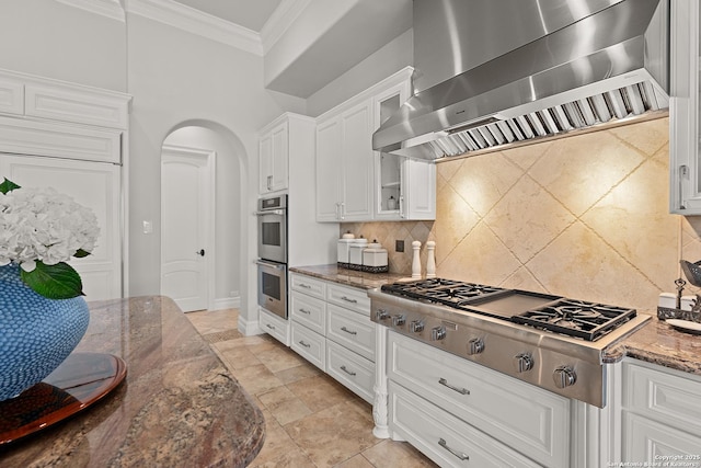 kitchen featuring extractor fan, stainless steel appliances, dark stone countertops, white cabinets, and ornamental molding