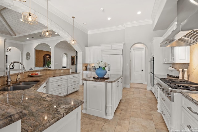 kitchen featuring stainless steel appliances, pendant lighting, a spacious island, white cabinetry, and range hood