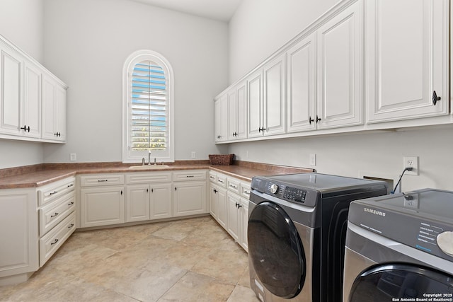 clothes washing area featuring sink, cabinets, and washing machine and clothes dryer