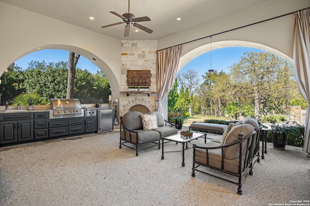 view of patio / terrace featuring an outdoor kitchen, grilling area, an outdoor stone fireplace, ceiling fan, and sink