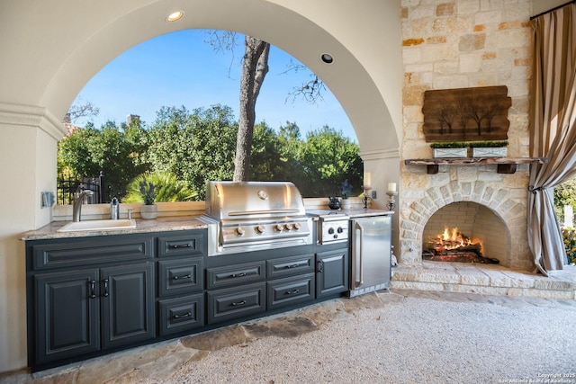 view of patio / terrace with sink, area for grilling, and an outdoor stone fireplace