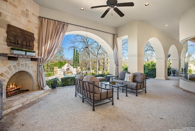 view of patio with ceiling fan and an outdoor living space with a fireplace