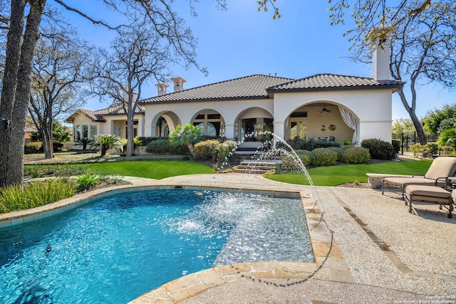 back of property with a yard, a patio, ceiling fan, and pool water feature