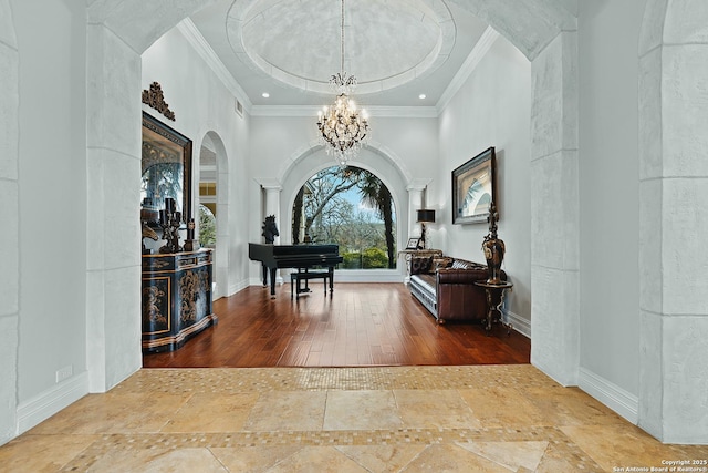 foyer entrance with a chandelier, crown molding, and decorative columns