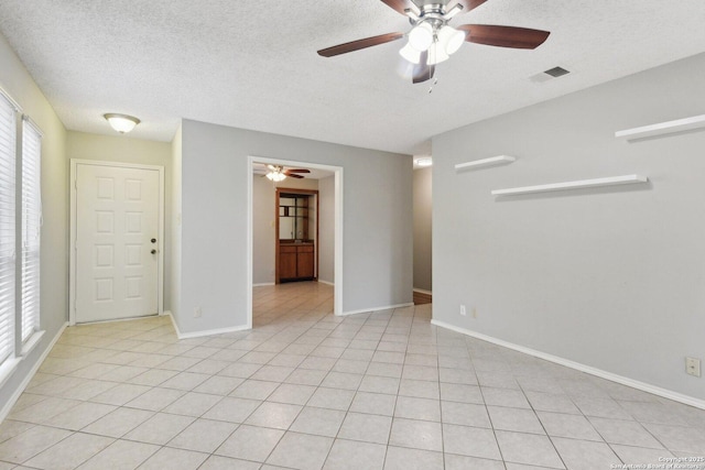 unfurnished room featuring a textured ceiling, ceiling fan, and light tile patterned flooring