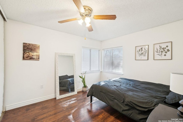 bedroom with a textured ceiling, ceiling fan, and dark hardwood / wood-style floors