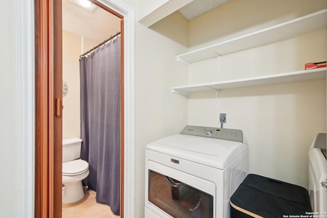 laundry area featuring a textured ceiling, washer / clothes dryer, and light tile patterned flooring