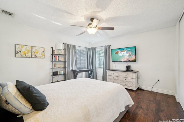 bedroom with ceiling fan, dark wood-type flooring, and a textured ceiling