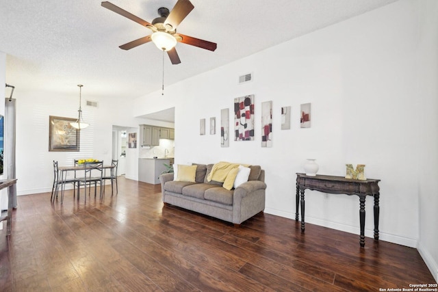 living room featuring a textured ceiling, ceiling fan, and dark hardwood / wood-style flooring