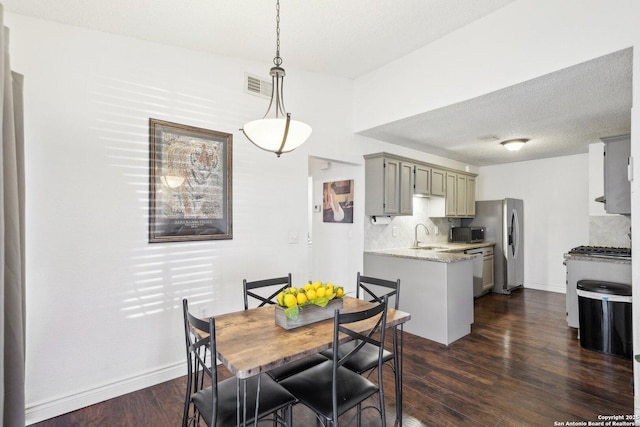 dining space with sink, a textured ceiling, and dark hardwood / wood-style floors