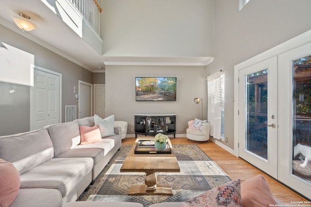 living room featuring a high ceiling, light hardwood / wood-style flooring, french doors, and crown molding