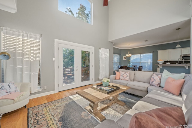 living room featuring a towering ceiling, french doors, ornamental molding, and light hardwood / wood-style flooring