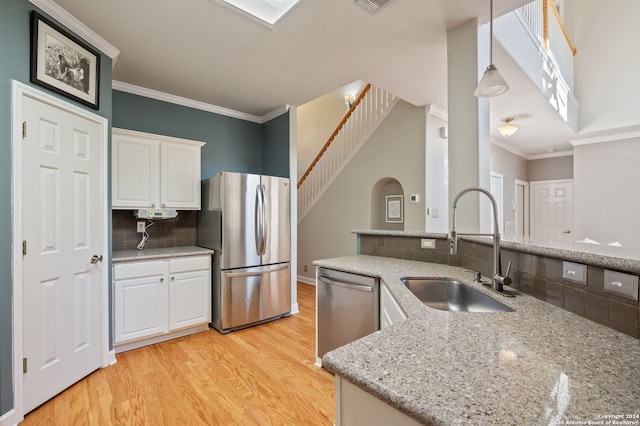 kitchen featuring appliances with stainless steel finishes, hanging light fixtures, light stone counters, sink, and white cabinetry