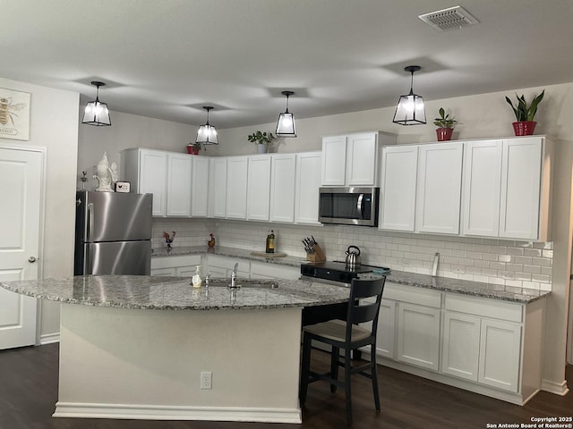 kitchen with stainless steel appliances, white cabinets, and decorative light fixtures