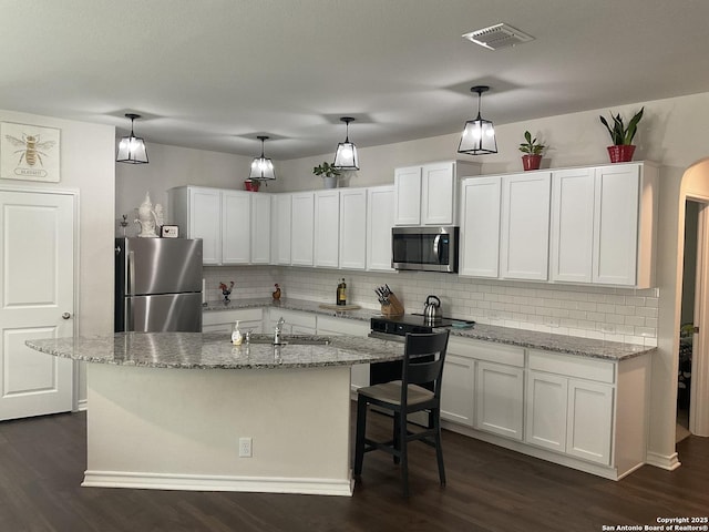 kitchen featuring white cabinetry, tasteful backsplash, an island with sink, and appliances with stainless steel finishes