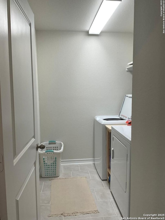 washroom with washing machine and clothes dryer and light tile patterned floors