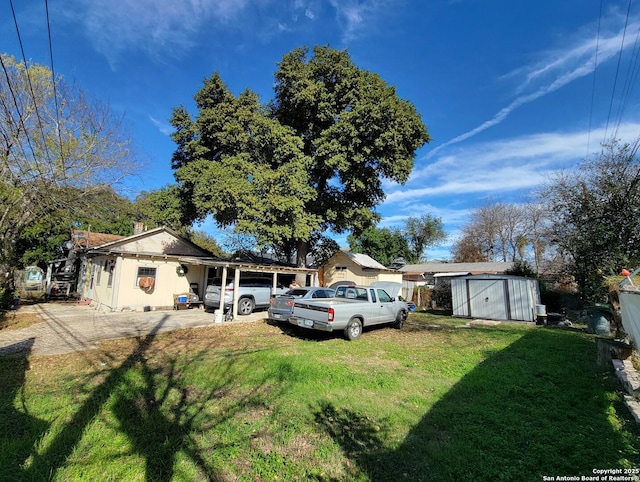 view of front of property featuring a storage unit, a carport, and a front lawn