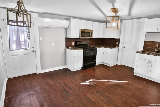 kitchen with a textured ceiling, a wall unit AC, decorative light fixtures, white cabinets, and black electric range