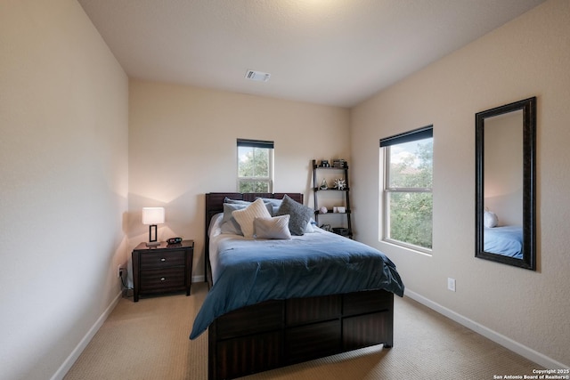 bedroom with light carpet and multiple windows